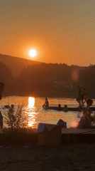 Lake swimmers enjoy a warm golden-hour sunset together