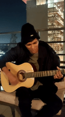 Outdoor late-night acoustic guitar session with city backdrop
