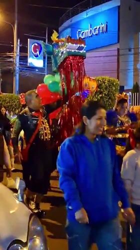 Costumed nighttime parade with dragon, clown figures in Arequipa