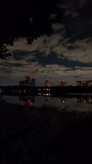Moscow waterfront at night, apartment lights reflected on still water