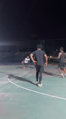 Young men play nighttime basketball on illuminated outdoor court