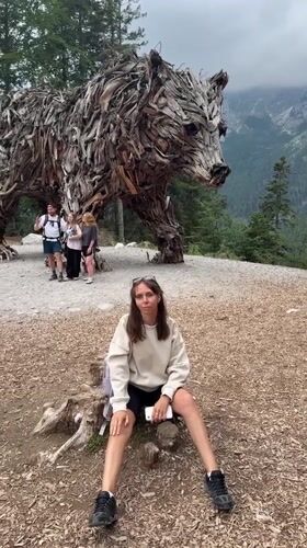 Driftwood bear sculpture and alpine meadows in Molveno