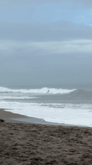 Surfers ride waves at cloudy North Kuta beach