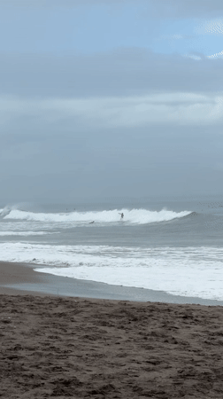 Surfers ride waves at cloudy North Kuta beach