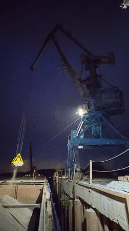 Night crane operations load material onto barge in Tver