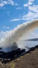 Waves crash against rocky shore under cloudy sky