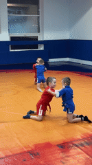 Young boys practice wrestling in indoor training facility