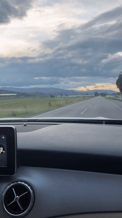 Woman drives through rural Bulgaria amid dramatic skies