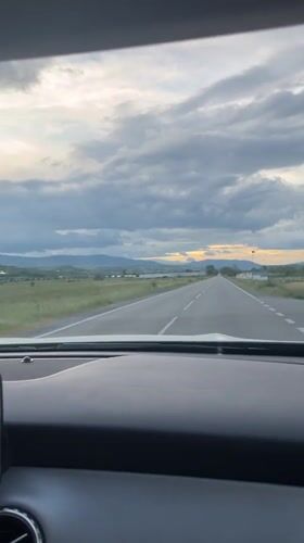 Woman drives through rural Bulgaria amid dramatic skies