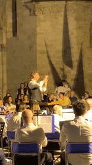 Outdoor brass concert at a historic San Quirico d'Orcia stone venue