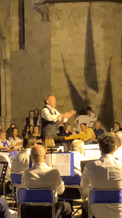 Outdoor brass concert at a historic San Quirico d'Orcia stone venue