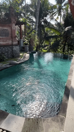 Woman takes morning selfies at tropical pool in Ubud