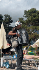 Street musician serenades beachgoers with accordion in Budva