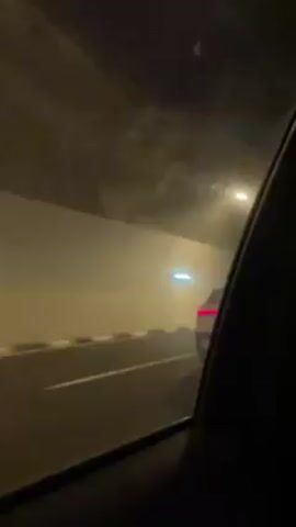 The video shows the interior of a car traveling through a tunnel. The window of the car is dirty. There are lights on the ceiling of the tunnel.
