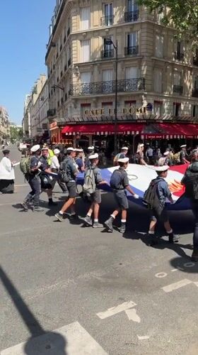 Uniformed youth procession with flags marches through central Paris