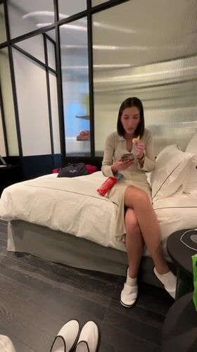 Woman relaxes with snacks and phone in Tbilisi hotel room
