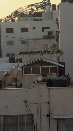 Gaza City skyline at sunset, damage and debris visible across rooftops