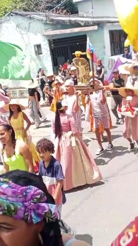 Traditional parade with flags and religious statue in Tinaquillo