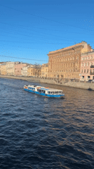 Passenger boat cruises Saint Petersburg canal under clear skies