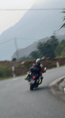 Motorcycle duo navigates mountain road in Vietnamese commune