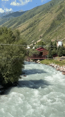 Riverside mountain resort stop, Cyrillic signage, turquoise glacial river