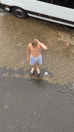 Man stands shirtless in heavy London downpour