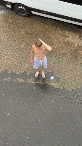 Man stands shirtless in heavy London downpour