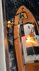 Maritime workers handle illuminated boat in choppy Ibiza waters