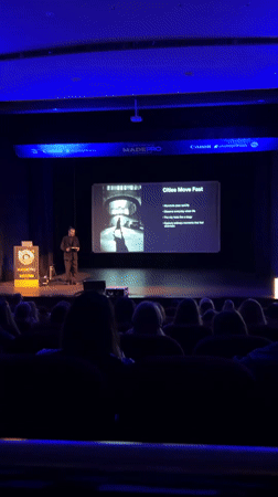 Man gives presentation at Pomorie auditorium with blue stage lighting