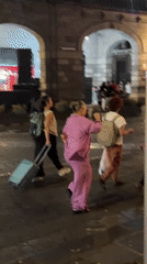 Night scene: women with luggage, tourist bus in Puebla square