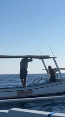 Traditional outrigger boats in open Indonesian waters, people aboard and swimming