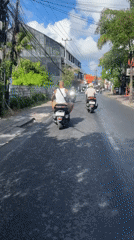 Two riders travel by moped through North Kuta streets
