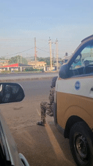 Man sits beside marked van in Ilorin roadside scene