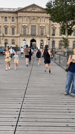 Runners cross wooden bridge near the Louvre, Paris