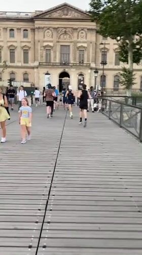 Runners cross wooden bridge near the Louvre, Paris