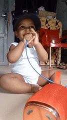 Toddler plays with speaker and cord on tiled floor