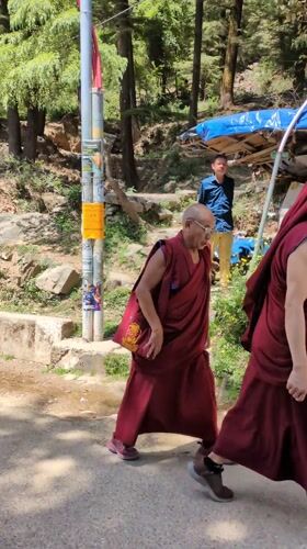 Buddhist monks walk paved road in sunny Dharamshala