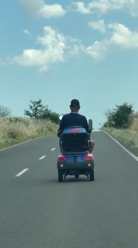 Mobility scooter rolling down a paved road in Krustina