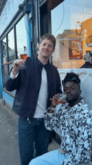 Two men share wine outdoors in London evening