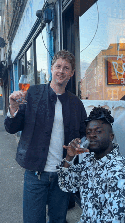 Two men share wine outdoors in London evening