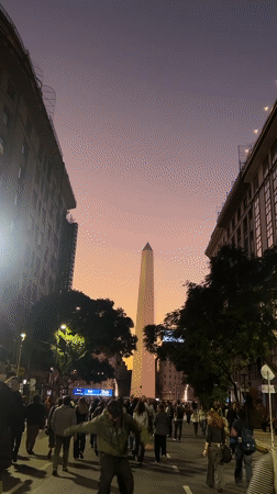 Evening crowds gather around Buenos Aires Obelisco monument