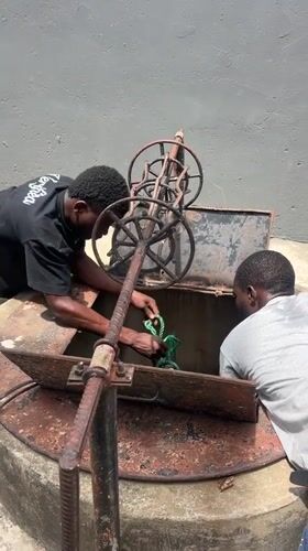 Two workers maintain rusted well in Lagos
