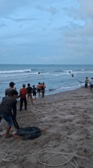 Fishermen pull nets onto beach in Lhokseumawe, Indonesia
