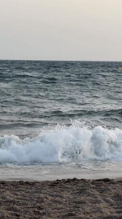 Dusk at a dark sand beach, lighthouse on the horizon