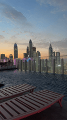 Empty rooftop pool overlooks Dubai skyline at dusk