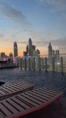 Empty rooftop pool overlooks Dubai skyline at dusk