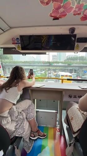 Tourist documents morning street scenes from Guangzhou tour bus