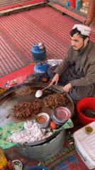 Street vendor cooks meat at outdoor market in Quetta