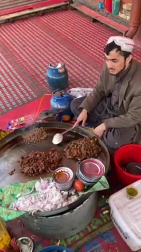 Street vendor cooks meat at outdoor market in Quetta