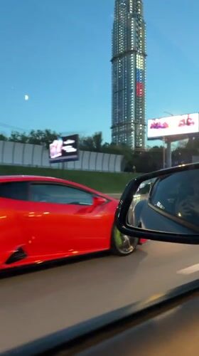 Red Lamborghini cruises Moscow highway at dusk
